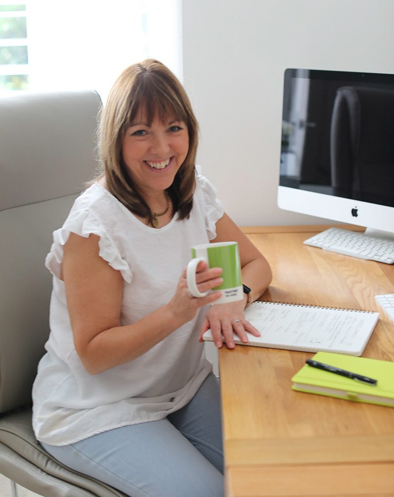Jeanette at her desk drinking tea in a green mug